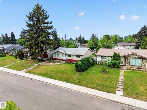 Ranch-style residence featuring a prominent front lawn with established landscaping, a concrete sidewalk leading to the front entry, and a paved road frontage with a concrete curb - 5216 104A Street, Edmonton, AB - Outdoor With Facade