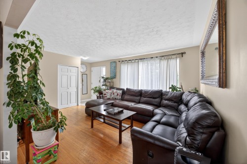Living area featuring wood-finish flooring, light-toned walls, and a large window with privacy coverings - 5216 104A Street, Edmonton, AB - Indoor Photo Showing Living Room