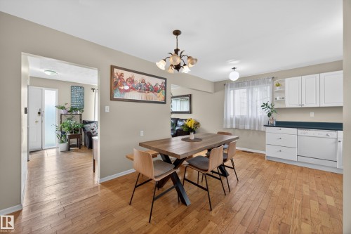 Hardwood-finish flooring throughout, featuring a kitchen with white cabinetry and a dark countertop - 5216 104A Street, Edmonton, AB - Indoor Photo Showing Other Room
