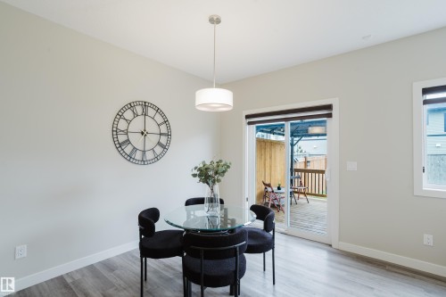 Bright dining area featuring wood-finish flooring, a contemporary pendant light fixture, and light-toned walls - 9142 Pear Drive, Edmonton, AB - Indoor Photo Showing Dining Room