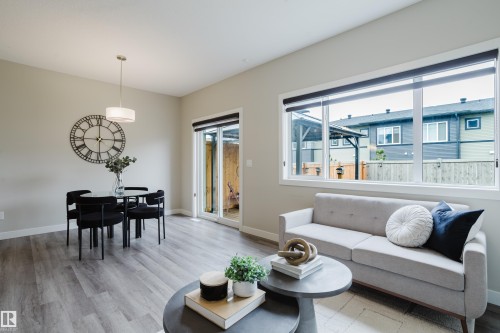 Open-concept living space with wood-finish flooring, a contemporary drum pendant light, and a sliding glass door leading to the exterior - 9142 Pear Drive, Edmonton, AB - Indoor