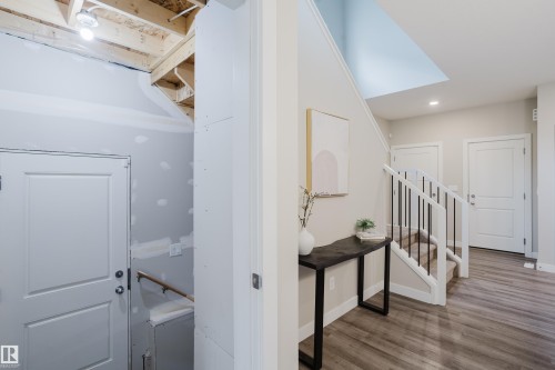 Entryway featuring wood-finish flooring, a carpeted staircase with white risers, and black metal balusters - 9142 Pear Drive, Edmonton, AB - Indoor Photo Showing Other Room