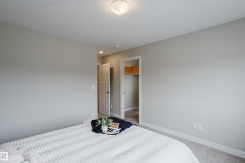 Spacious room featuring neutral paint, soft carpet, a paneled door, and a closet with wire shelving - 9142 Pear Drive, Edmonton, AB - Indoor Photo Showing Bedroom