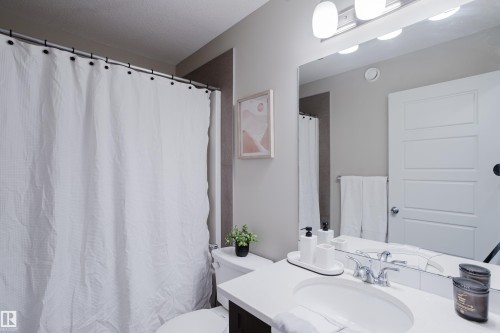 Bathroom featuring a vanity with an integrated sink, polished chrome faucet, and a large wall-mounted mirror with overhead lighting - 9142 Pear Drive, Edmonton, AB - Indoor Photo Showing Bathroom
