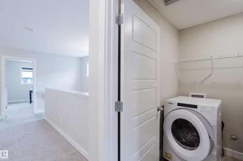 Dedicated laundry area featuring a front-loading washer, wire shelving, and neutral wall tones - 9142 Pear Drive, Edmonton, AB - Indoor Photo Showing Laundry Room