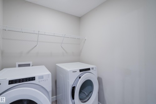 Dedicated laundry area featuring a white wire shelf, light-toned walls, and wood-finish flooring - 9142 Pear Drive, Edmonton, AB - Indoor Photo Showing Laundry Room