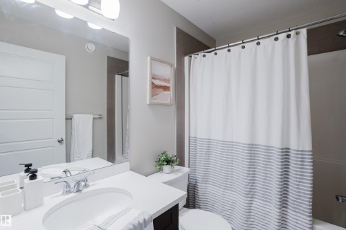 Bathroom featuring a single vanity with a white countertop, chrome faucet, and a large mirror with integrated lighting - 9142 Pear Drive, Edmonton, AB - Indoor Photo Showing Bathroom