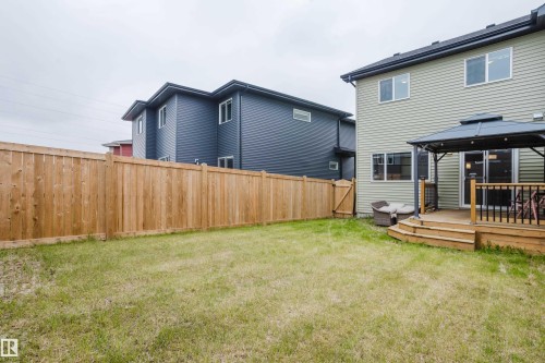Expansive backyard featuring a natural wood privacy fence, a wooden deck with railing, and a dark-canopied gazebo - 9142 Pear Drive, Edmonton, AB - Outdoor With Deck Patio Veranda