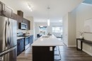 Modern kitchen featuring dark wood-finish cabinetry, stainless steel appliances, a white subway tile backsplash, and a large central island with a white countertop and integrated sink - 9142 Pear Drive, Edmonton, AB  - Indoor Photo Showing Kitchen With Upgraded Kitchen 