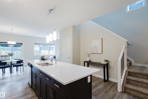 Spacious kitchen island with a white countertop and dark cabinetry featuring an integrated double-basin sink and pendant lighting - 9142 Pear Drive, Edmonton, AB - Indoor Photo Showing Kitchen With Double Sink