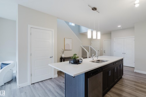 Kitchen island featuring a double-basin sink, stainless steel dishwasher, and pendant lighting - 9142 Pear Drive, Edmonton, AB - Indoor Photo Showing Kitchen With Double Sink