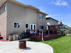 Expansive stucco exterior with multiple windows and double French doors opening to a large wooden deck. - 
