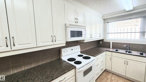 White cabinetry with brushed nickel hardware, speckled countertops, and a tiled backsplash - 8824 90 Street, Edmonton, AB 