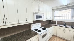 White cabinetry with brushed nickel hardware, speckled countertops, and a tiled backsplash - 