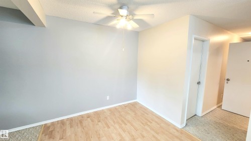 Room featuring wood-finish flooring, a neutral color palette, and a ceiling fan with integrated lighting - 8824 90 Street, Edmonton, AB 