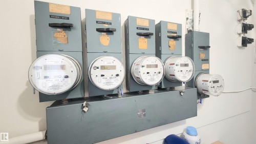 Utility meters and electrical panels mounted on a white wall - 8824 90 Street, Edmonton, AB 
