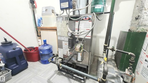 Utility area featuring a water filtration system, furnace, and exposed piping - 8824 90 Street, Edmonton, AB 