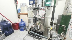 Utility area featuring a water filtration system, furnace, and exposed piping - 