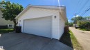 Detached garage featuring white vinyl siding, a white overhead door, and concrete driveway - 8824 90 Street, Edmonton, AB 