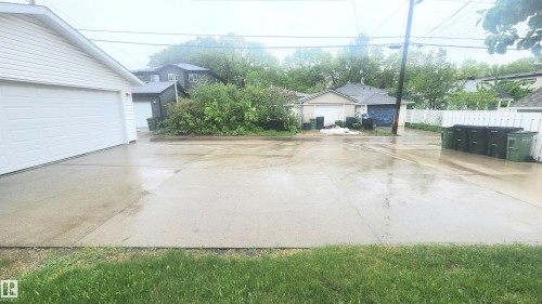Concrete driveway with an attached garage featuring white siding and a white overhead door - 8824 90 Street, Edmonton, AB 