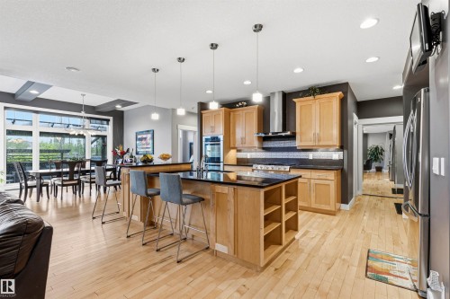 Open-concept kitchen featuring light wood cabinetry, dark countertops, and stainless steel appliances - 5709 Mcluhan Bay, Edmonton, AB 