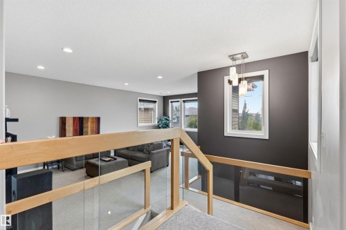Staircase featuring wood-finish handrails and glass panels - 5709 Mcluhan Bay, Edmonton, AB 