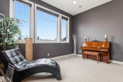 Spacious room featuring three large windows, dark gray walls, recessed lighting, and light-toned carpeting - 