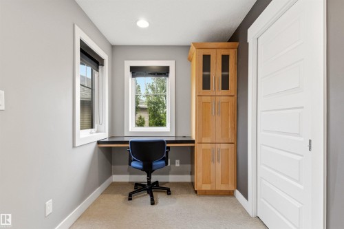 Dedicated workspace featuring a built-in desk, two windows, recessed lighting, built-in cabinetry with glass-front uppers, and carpeting - 5709 Mcluhan Bay, Edmonton, AB 
