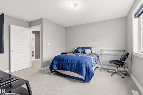 Neutral-toned bedroom featuring light gray walls, plush carpeting, and a white paneled interior door - 5709 Mcluhan Bay, Edmonton, AB 