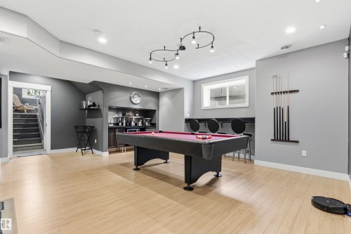 Open recreation space featuring light wood-finish flooring, recessed lighting, and a built-in wet bar with dark cabinetry - 5709 Mcluhan Bay, Edmonton, AB 
