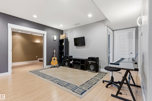 Spacious entertainment area with light wood-finish flooring, recessed lighting, and a white interior door - 5709 Mcluhan Bay, Edmonton, AB 