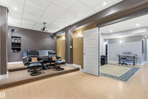 Dedicated media room featuring a raised carpeted platform, recessed lighting, built-in shelving, and light wood-finish flooring - 5709 Mcluhan Bay, Edmonton, AB 