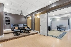 Dedicated media room featuring a raised carpeted platform, recessed lighting, built-in shelving, and light wood-finish flooring - 