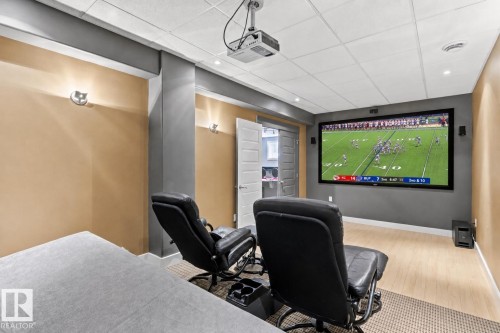 Dedicated media room featuring a large projection screen, ceiling-mounted projector, recessed lighting, and sconce lighting - 5709 Mcluhan Bay, Edmonton, AB 