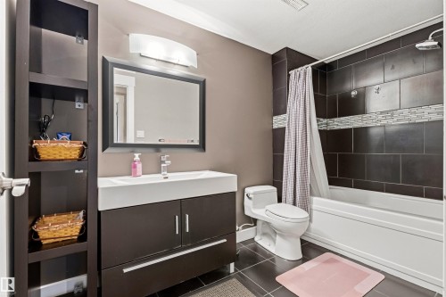 Full bathroom featuring a dark tile bath/shower surround with a mosaic accent band - 5709 Mcluhan Bay, Edmonton, AB 