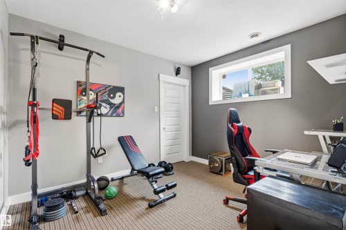 Versatile bonus room featuring durable carpet flooring, a window providing natural light, and a white paneled door - 5709 Mcluhan Bay, Edmonton, AB 