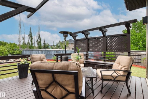 Expansive wood deck with a privacy screen featuring latticework detailing, a built-in bench, and a dark wood pergola structure - 5709 Mcluhan Bay, Edmonton, AB 
