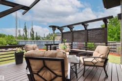 Expansive wood deck with a privacy screen featuring latticework detailing, a built-in bench, and a dark wood pergola structure - 