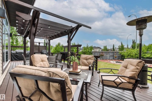 Spacious wood-finish deck with a built-in pergola featuring string lighting - 5709 Mcluhan Bay, Edmonton, AB 