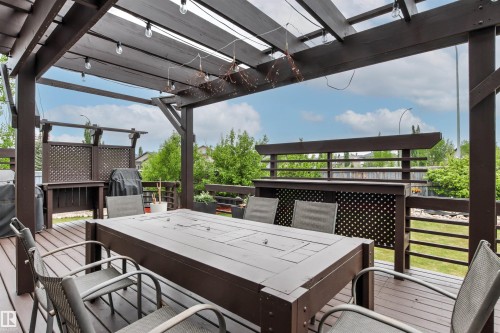 Expansive outdoor deck featuring a dark wood pergola, string lighting, composite decking, and perimeter railing - 5709 Mcluhan Bay, Edmonton, AB 