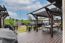Expansive multi-level wood deck featuring a pergola with string lighting - 