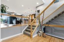 Multi-level interior featuring wood-finish flooring, a glass and wood railing, recessed lighting, a carpeted staircase, and an open concept layout - 5709 Mcluhan Bay, Edmonton, AB 