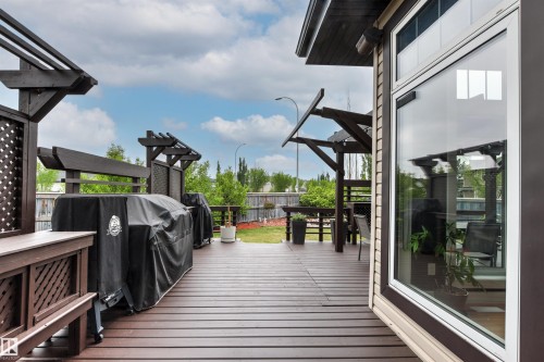 Expansive brown wood-finish deck with integrated pergola structures, lattice privacy screens, and a large sliding glass door - 5709 Mcluhan Bay, Edmonton, AB 