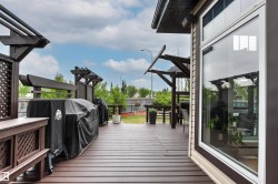 Expansive brown wood-finish deck with integrated pergola structures, lattice privacy screens, and a large sliding glass door - 