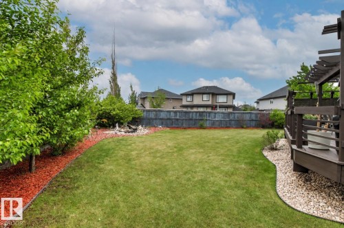 Expansive backyard featuring a lush lawn, a composite deck with pergola, and a decorative rock garden - 5709 Mcluhan Bay, Edmonton, AB 