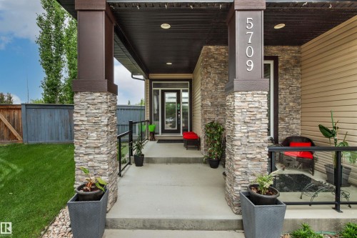 Covered entryway featuring stone veneer columns and tan siding - 5709 Mcluhan Bay, Edmonton, AB 
