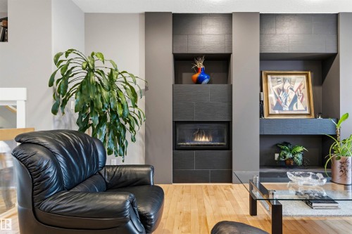 Modern fireplace feature wall with dark gray tile surround and integrated shelving - 5709 Mcluhan Bay, Edmonton, AB 