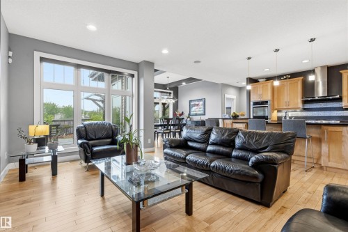 Open-concept living area featuring light wood-finish flooring, recessed ceiling lighting, and a kitchen with light wood cabinetry - 5709 Mcluhan Bay, Edmonton, AB 
