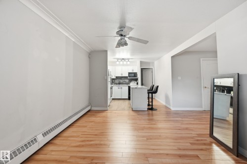 Open-concept living area featuring wood-finish flooring, crown molding, and a ceiling fan - 33 9914 80 Avenue, Edmonton, AB - Indoor
