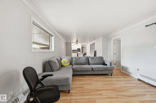 Open-concept living area with wood-finish flooring, light gray walls, and white crown molding - 33 9914 80 Avenue, Edmonton, AB - Indoor Photo Showing Living Room